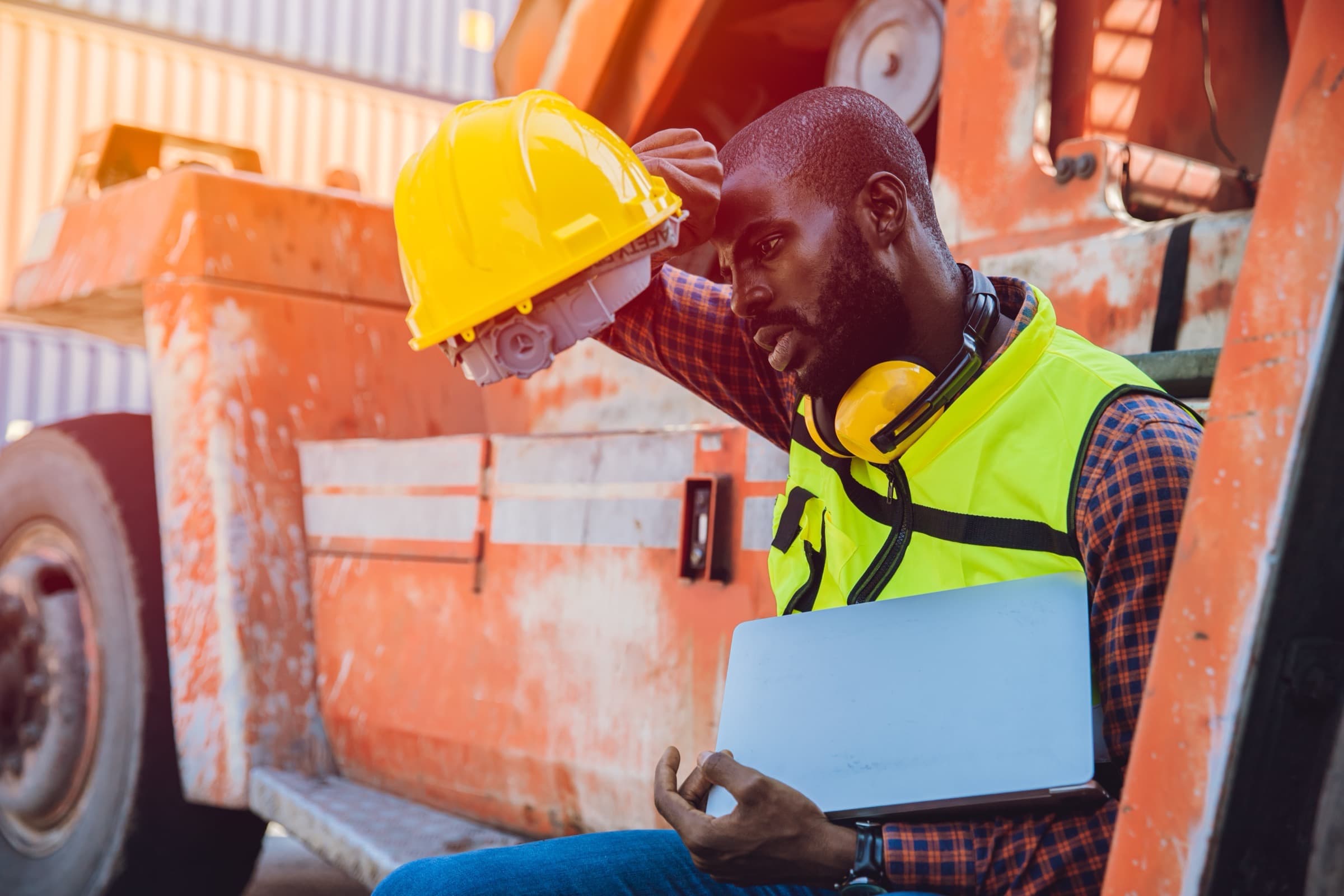 A longshoreman reviewing paperwork beside heavy equipment